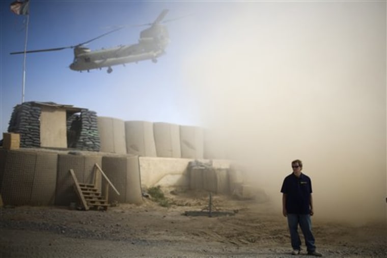 A U.S. contractor looks away from a dust cloud whipped up by a helicopter departing over the gatepost at Combat Outpost Terra Nova in Kandahar, Afghanistan on July 19.